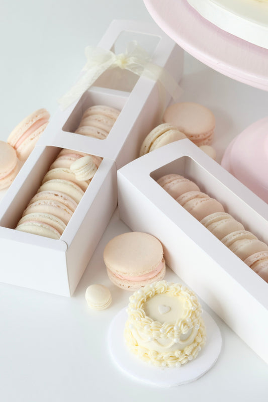 Pink macarons in box with white mini vintage cake
